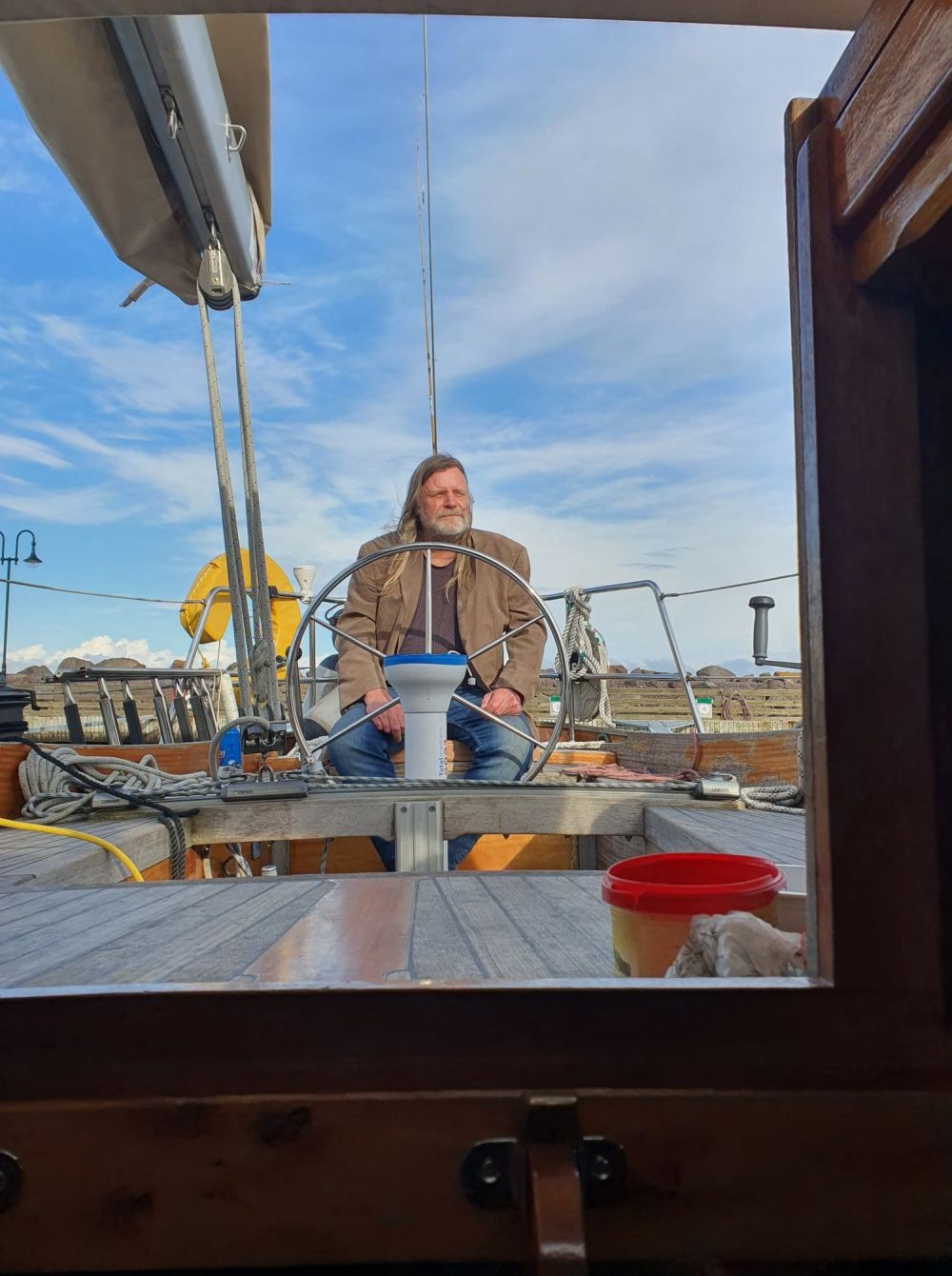 Ved roret på Ariadne, sett gjennom lugardøren